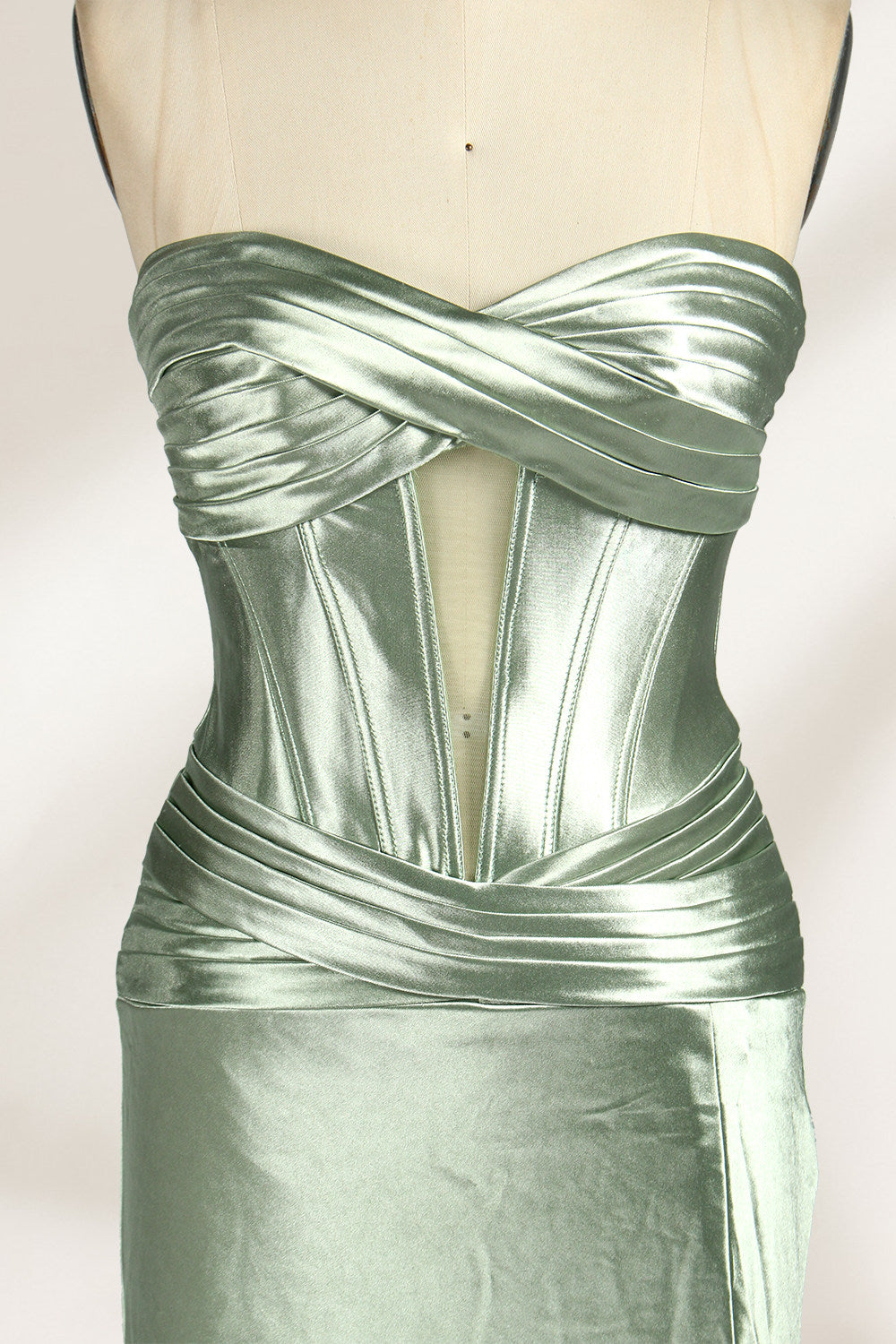 A mannequin showcases a strapless light - green satin gown against a soft, neutral backdrop. The dress features a twisted, criss - cross bodice with a subtle sheer panel and a mermaid silhouette, complete with a high side slit and a flowing train. The smooth, lustrous satin fabric and elegant design exude sophistication, perfect for formal galas or black - tie events.21