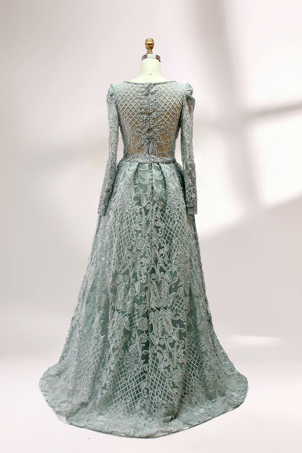 Displayed on a mannequin is a light - gray evening gown. It has a deep V - neckline, long sleeves, and intricate lace embroidery with a grid pattern. The elegant design gives off a luxurious and sophisticated vibe, ideal for formal occasions.2