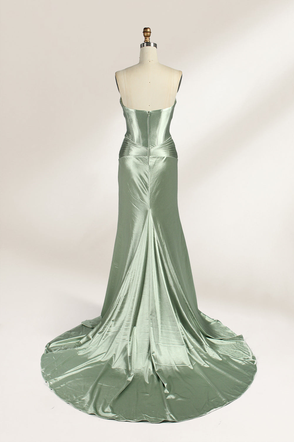 A mannequin showcases a strapless light - green satin gown against a soft, neutral backdrop. The dress features a twisted, criss - cross bodice with a subtle sheer panel and a mermaid silhouette, complete with a high side slit and a flowing train. The smooth, lustrous satin fabric and elegant design exude sophistication, perfect for formal galas or black - tie events.5