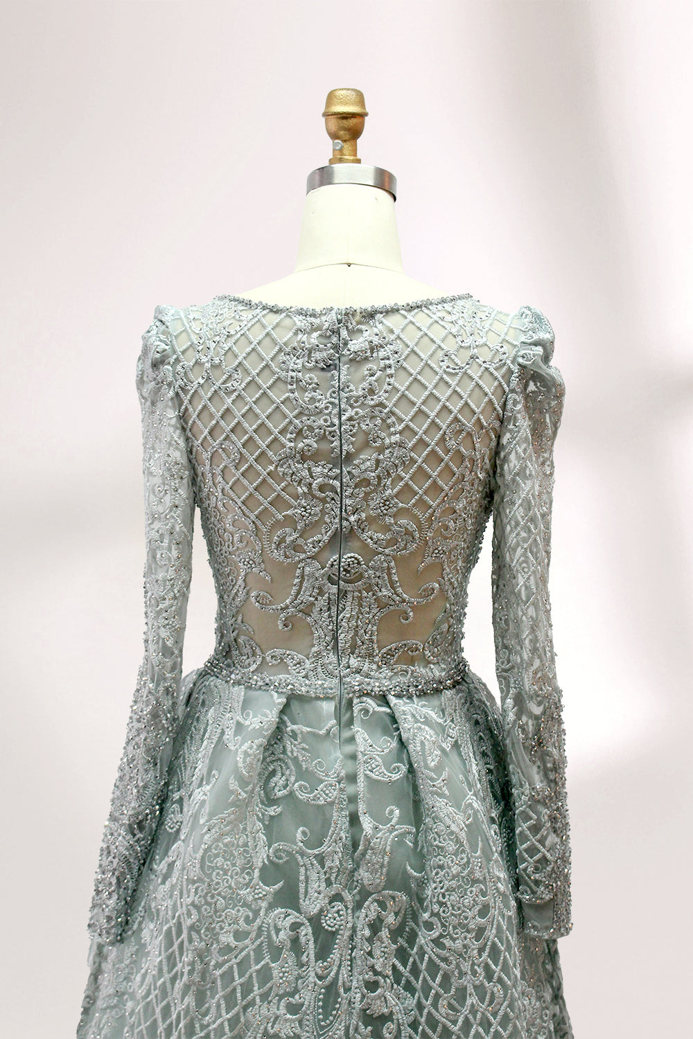 Displayed on a mannequin is a light - gray evening gown. It has a deep V - neckline, long sleeves, and intricate lace embroidery with a grid pattern. The elegant design gives off a luxurious and sophisticated vibe, ideal for formal occasions.7