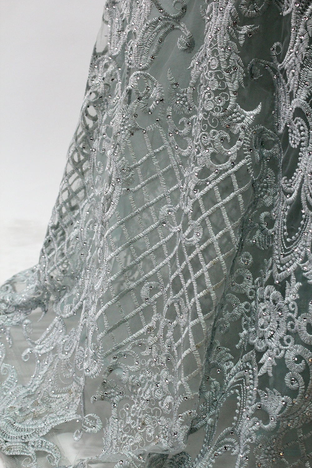 Displayed on a mannequin is a light - gray evening gown. It has a deep V - neckline, long sleeves, and intricate lace embroidery with a grid pattern. The elegant design gives off a luxurious and sophisticated vibe, ideal for formal occasions.10
