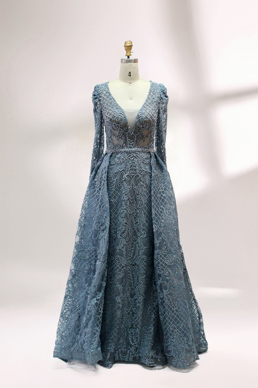 Displayed on a mannequin is a light - gray evening gown. It has a deep V - neckline, long sleeves, and intricate lace embroidery with a grid pattern. The elegant design gives off a luxurious and sophisticated vibe, ideal for formal occasions.5