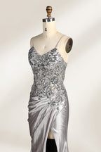 Photograph of a mannequin wearing a stunning, floor-length, navy blue satin evening gown. The gown features a deep V-back with thin straps and intricate sequin detailing along the back and neckline. The fitted bodice gradually flares into a flowing, elegant train. The mannequin stands against a plain, light beige backdrop, highlighting the gown's luxurious texture and shimmering finish. The gown exudes sophistication and glamour, ideal for formal events.6