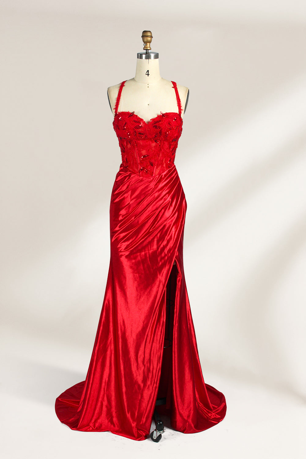On a mannequin against a light background, there’s a red satin gown. It has thin, delicate straps and a sweetheart neckline. The bodice is adorned with sequin - detailed lace, adding a touch of glamour. The skirt, ruched and mermaid - shaped, features a high side slit and a flowing train. The shiny satin fabric and sequin embellishments make it perfect for formal events like galas.1