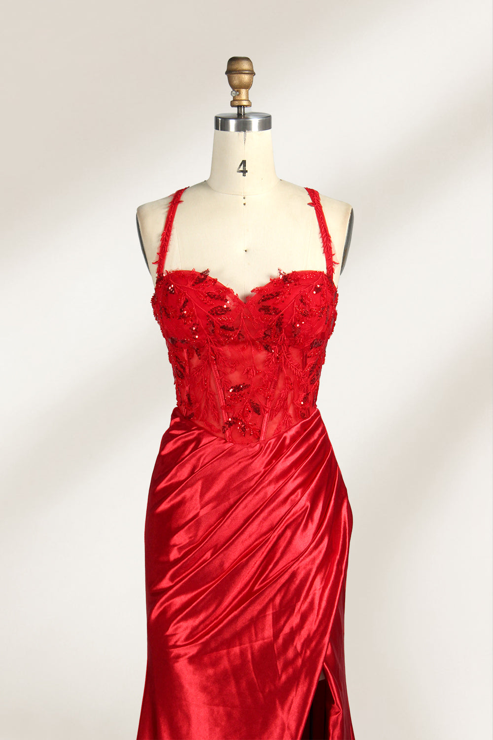 On a mannequin against a light background, there’s a red satin gown. It has thin, delicate straps and a sweetheart neckline. The bodice is adorned with sequin - detailed lace, adding a touch of glamour. The skirt, ruched and mermaid - shaped, features a high side slit and a flowing train. The shiny satin fabric and sequin embellishments make it perfect for formal events like galas.5