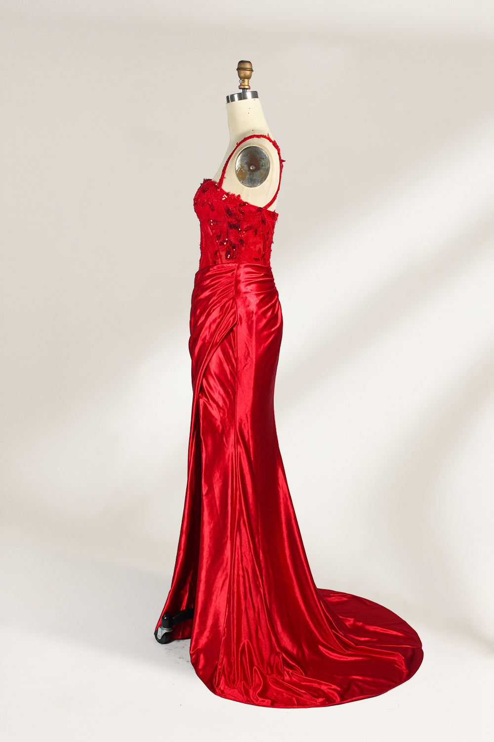 On a mannequin against a light background, there’s a red satin gown. It has thin, delicate straps and a sweetheart neckline. The bodice is adorned with sequin - detailed lace, adding a touch of glamour. The skirt, ruched and mermaid - shaped, features a high side slit and a flowing train. The shiny satin fabric and sequin embellishments make it perfect for formal events like galas.4