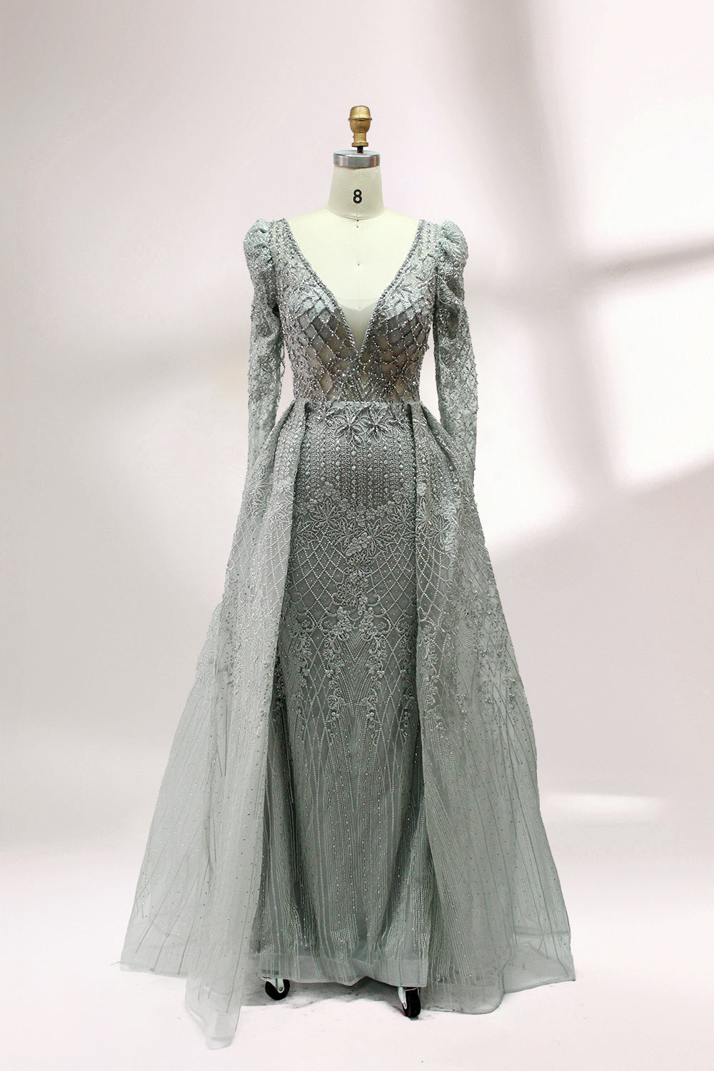 Illuminated softly, a mannequin showcases a light - gray evening gown. With a deep V - neckline, long puffed sleeves, and elaborate bead and lace embroidery, the gown exudes an air of luxury and sophistication, making it an excellent choice for formal galas and upscale events.1