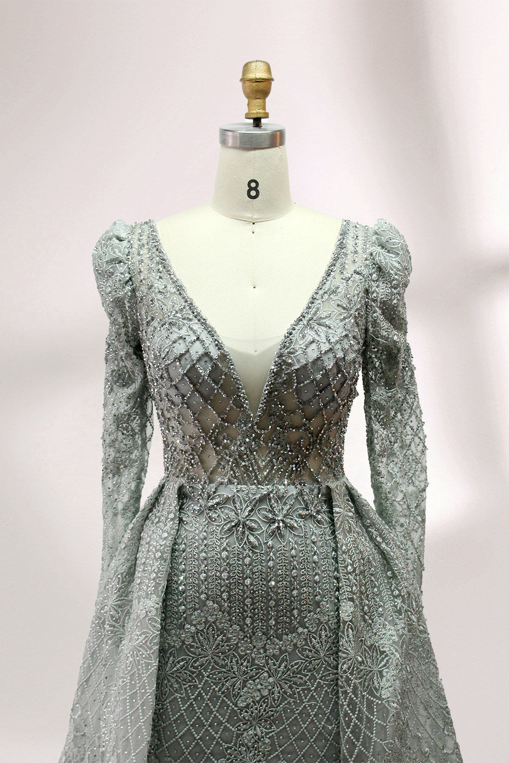 Illuminated softly, a mannequin showcases a light - gray evening gown. With a deep V - neckline, long puffed sleeves, and elaborate bead and lace embroidery, the gown exudes an air of luxury and sophistication, making it an excellent choice for formal galas and upscale events.7