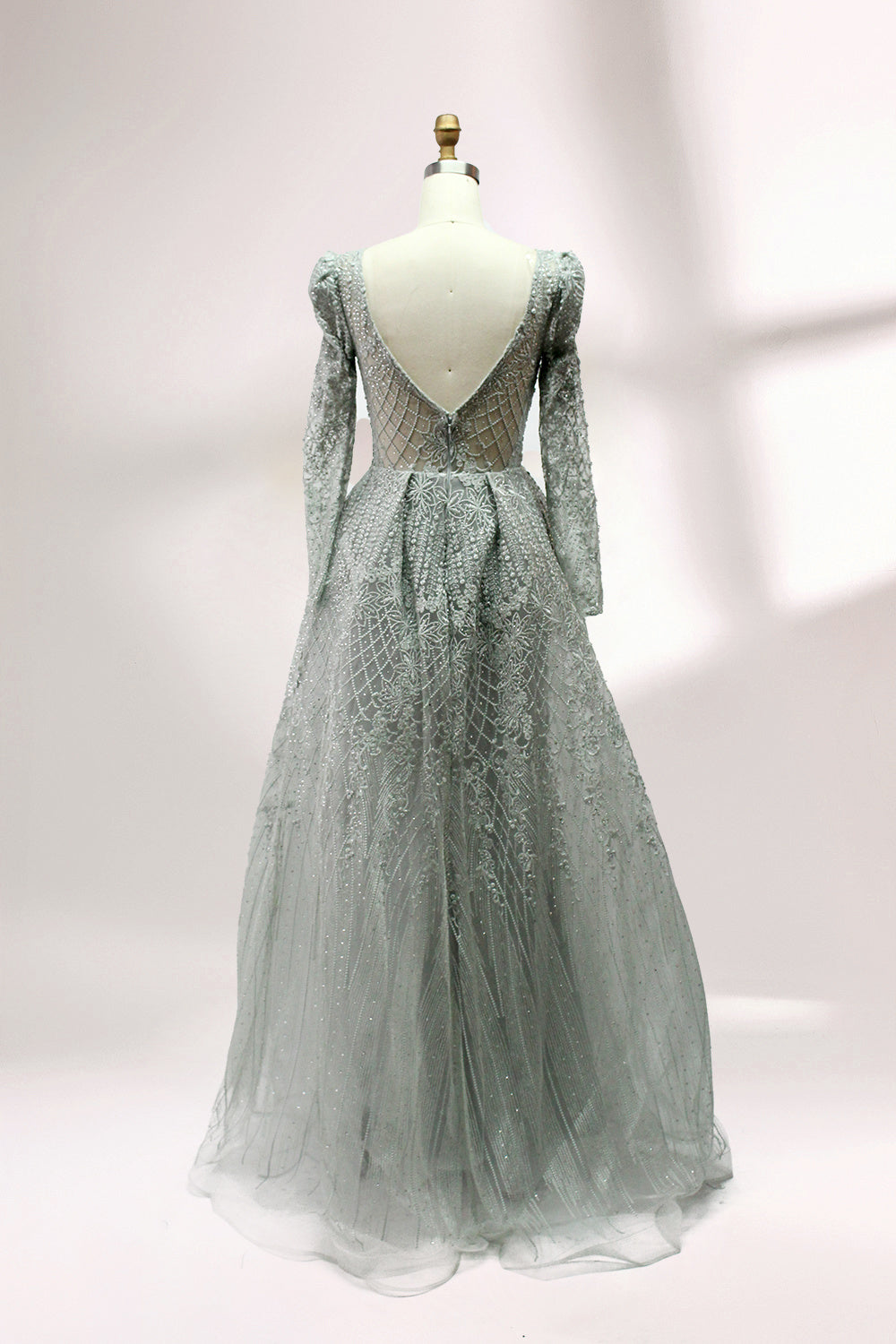 Illuminated softly, a mannequin showcases a light - gray evening gown. With a deep V - neckline, long puffed sleeves, and elaborate bead and lace embroidery, the gown exudes an air of luxury and sophistication, making it an excellent choice for formal galas and upscale events.2