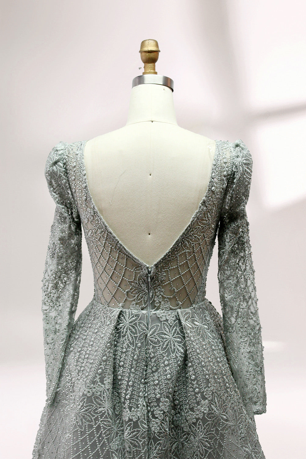 Illuminated softly, a mannequin showcases a light - gray evening gown. With a deep V - neckline, long puffed sleeves, and elaborate bead and lace embroidery, the gown exudes an air of luxury and sophistication, making it an excellent choice for formal galas and upscale events.8