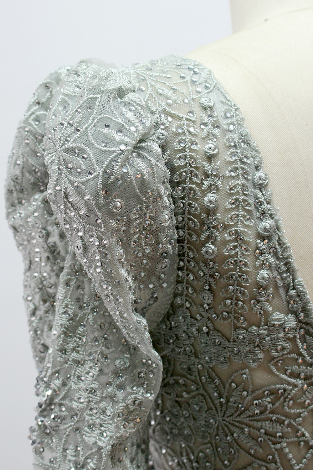 Illuminated softly, a mannequin showcases a light - gray evening gown. With a deep V - neckline, long puffed sleeves, and elaborate bead and lace embroidery, the gown exudes an air of luxury and sophistication, making it an excellent choice for formal galas and upscale events.9