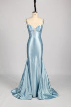 Photograph of a slender, fair-skinned woman with dark hair in an elegant updo, wearing a stunning, floor-length, light blue satin gown with a plunging neckline and thin spaghetti straps. The dress features a fitted bodice and a flowing skirt. She stands against a plain, light gray background, with soft lighting emphasizing the gown's sheen.9