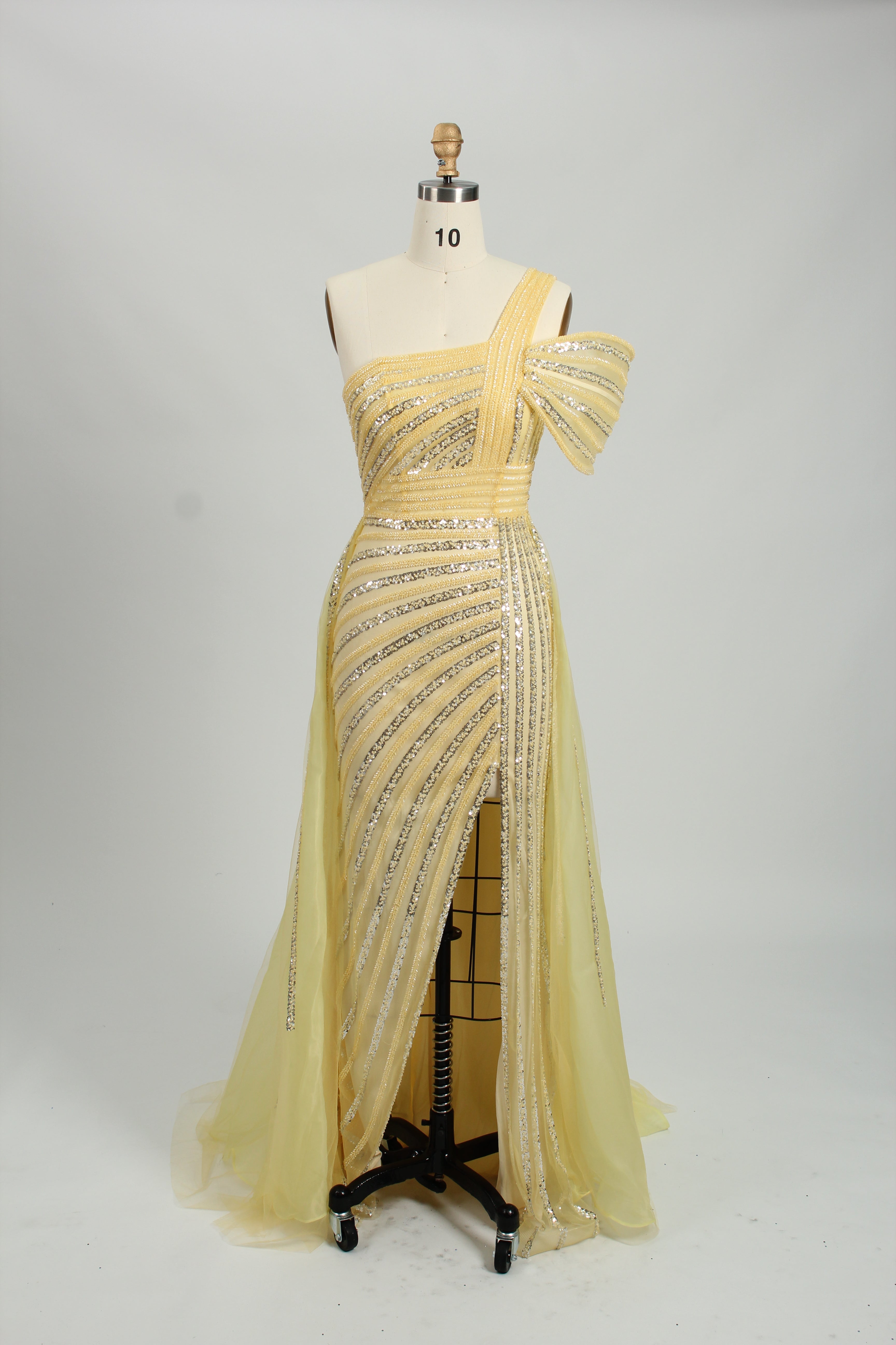 Against a light - hued backdrop, a woman dons a teal sequin gown with an one - shoulder design. It features a bow - detailed strap, a sheer waist panel, and a high side slit. The sparkling sequins and unique silhouette radiate glamour, perfect for formal dinners or galas.9