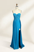 Photograph of a mannequin dressed in a strapless, floor-length, vibrant blue evening gown. The gown features intricate lace detailing across the bodice, with a fitted, corset-style silhouette. The skirt has a high slit on the right side, revealing black high heels underneath. The background is a plain, light beige, emphasizing the gown's shimmering texture and elegant design. The mannequin stands on a wooden base, labeled "4" on its neck.01