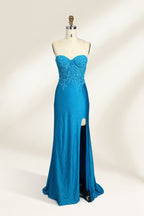 Photograph of a mannequin dressed in a strapless, floor-length, vibrant blue evening gown. The gown features intricate lace detailing across the bodice, with a fitted, corset-style silhouette. The skirt has a high slit on the right side, revealing black high heels underneath. The background is a plain, light beige, emphasizing the gown's shimmering texture and elegant design. The mannequin stands on a wooden base, labeled "4" on its neck.01