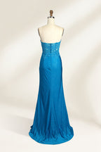 Photograph of a mannequin dressed in a strapless, floor-length, vibrant blue evening gown. The gown features intricate lace detailing across the bodice, with a fitted, corset-style silhouette. The skirt has a high slit on the right side, revealing black high heels underneath. The background is a plain, light beige, emphasizing the gown's shimmering texture and elegant design. The mannequin stands on a wooden base, labeled "4" on its neck.02