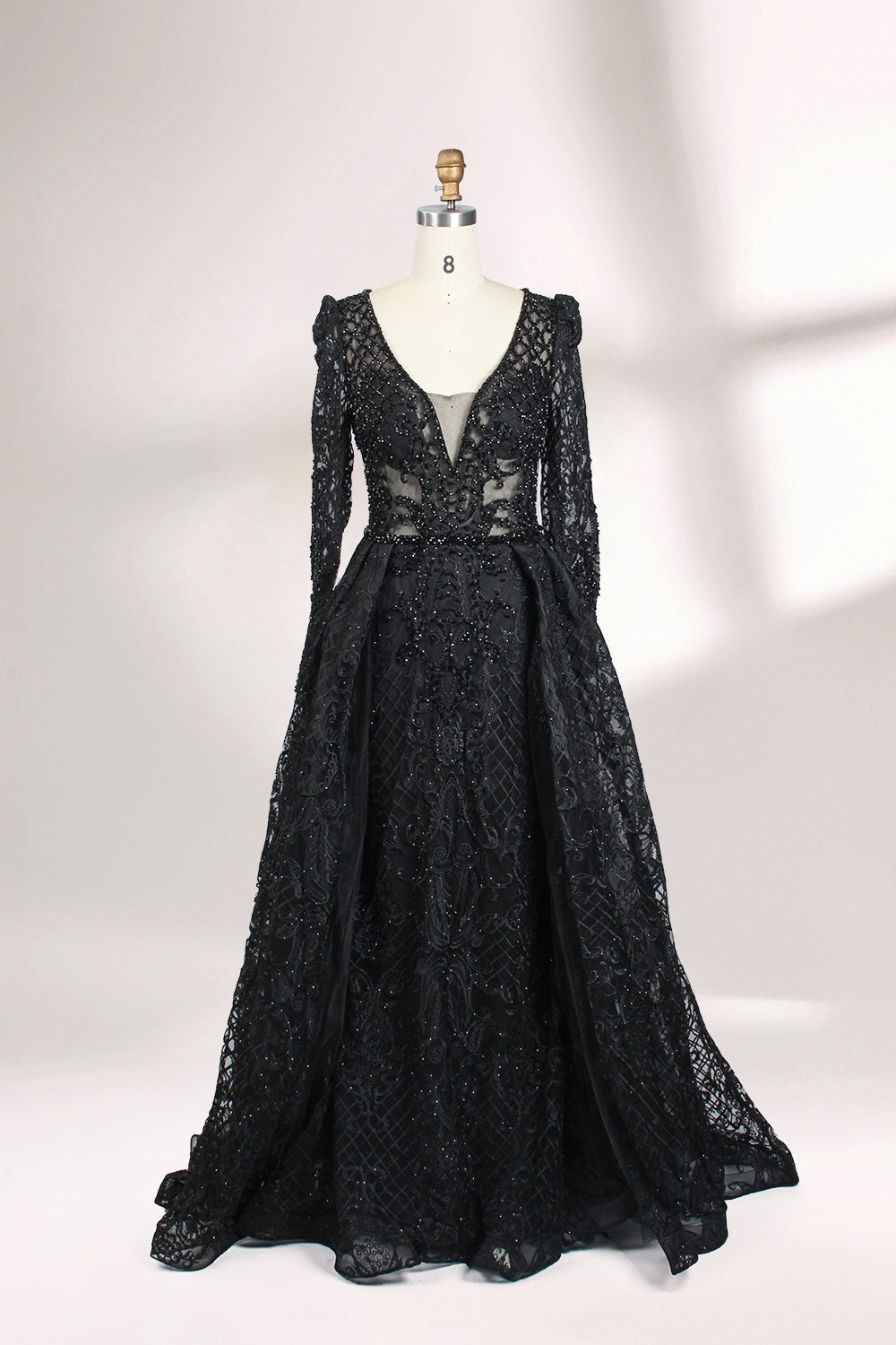 Displayed on a mannequin is a light - gray evening gown. It has a deep V - neckline, long sleeves, and intricate lace embroidery with a grid pattern. The elegant design gives off a luxurious and sophisticated vibe, ideal for formal occasions.6