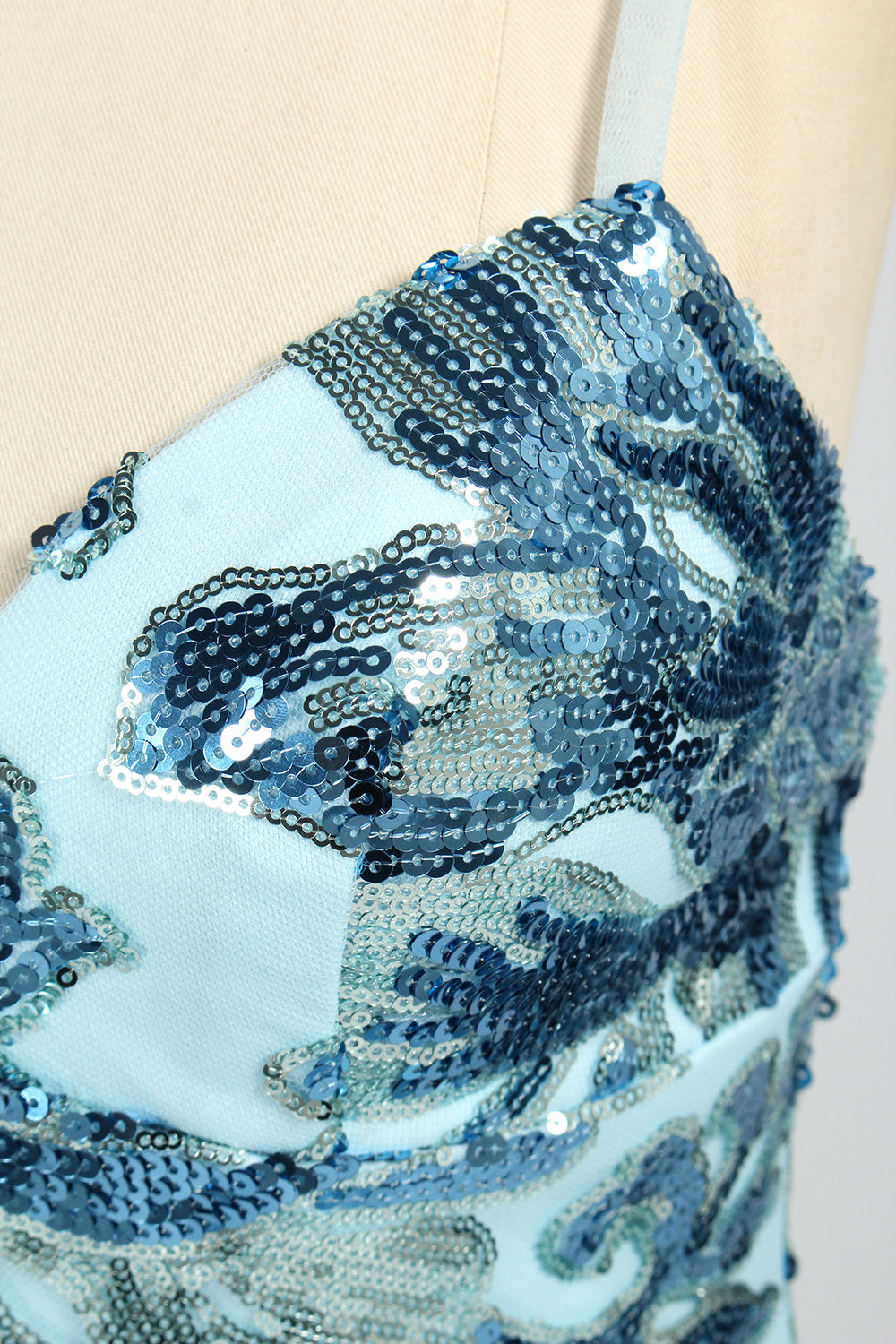 Set against a light background, a mannequin presents a light - blue tulle gown adorned with intricate floral sequin patterns. It has thin spaghetti straps, a sweetheart neckline, and a mermaid - shaped skirt with a high side slit. The shimmering sequins and delicate design create a glamorous look, ideal for proms or formal evening events.6