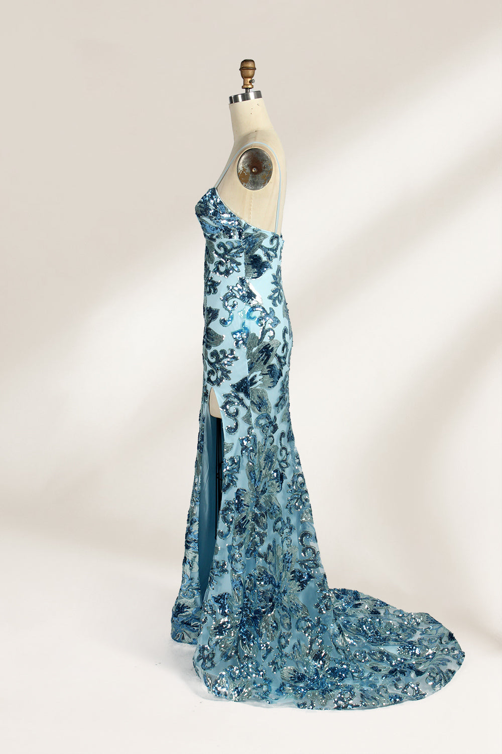 Set against a light background, a mannequin presents a light - blue tulle gown adorned with intricate floral sequin patterns. It has thin spaghetti straps, a sweetheart neckline, and a mermaid - shaped skirt with a high side slit. The shimmering sequins and delicate design create a glamorous look, ideal for proms or formal evening events.3