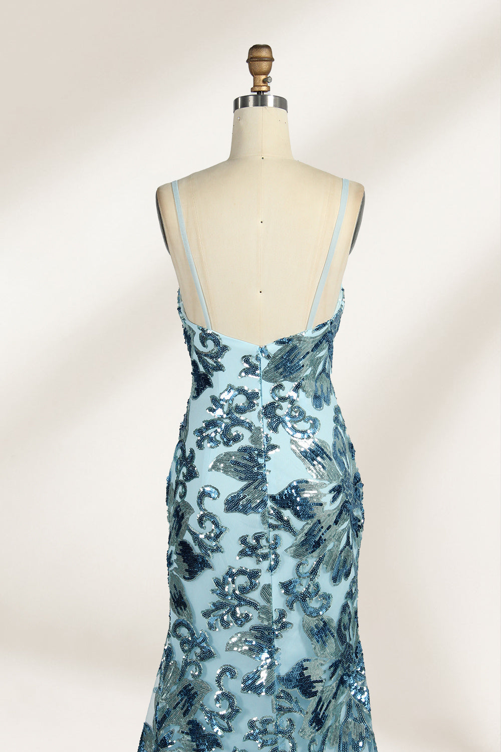 Set against a light background, a mannequin presents a light - blue tulle gown adorned with intricate floral sequin patterns. It has thin spaghetti straps, a sweetheart neckline, and a mermaid - shaped skirt with a high side slit. The shimmering sequins and delicate design create a glamorous look, ideal for proms or formal evening events.5