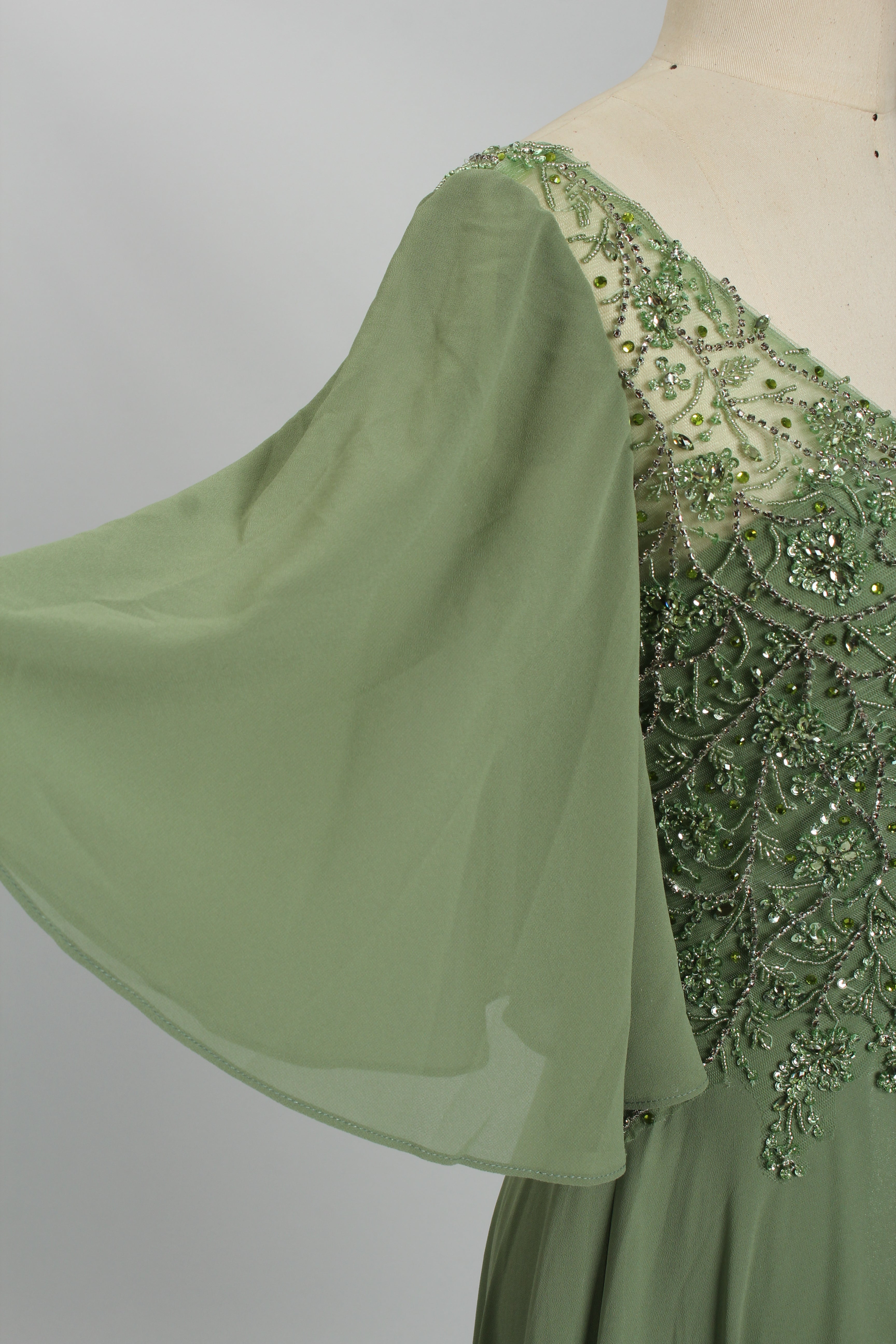 Front view of a charming sage green A-line mother of the bride dress featuring a V-neck beaded tulle bodice, elegant flowing ruffle sleeves, and a long floor-length chiffon skirt, suitable for weddings and formal evening galas and available for bulk sourcing or wholesale purchase.