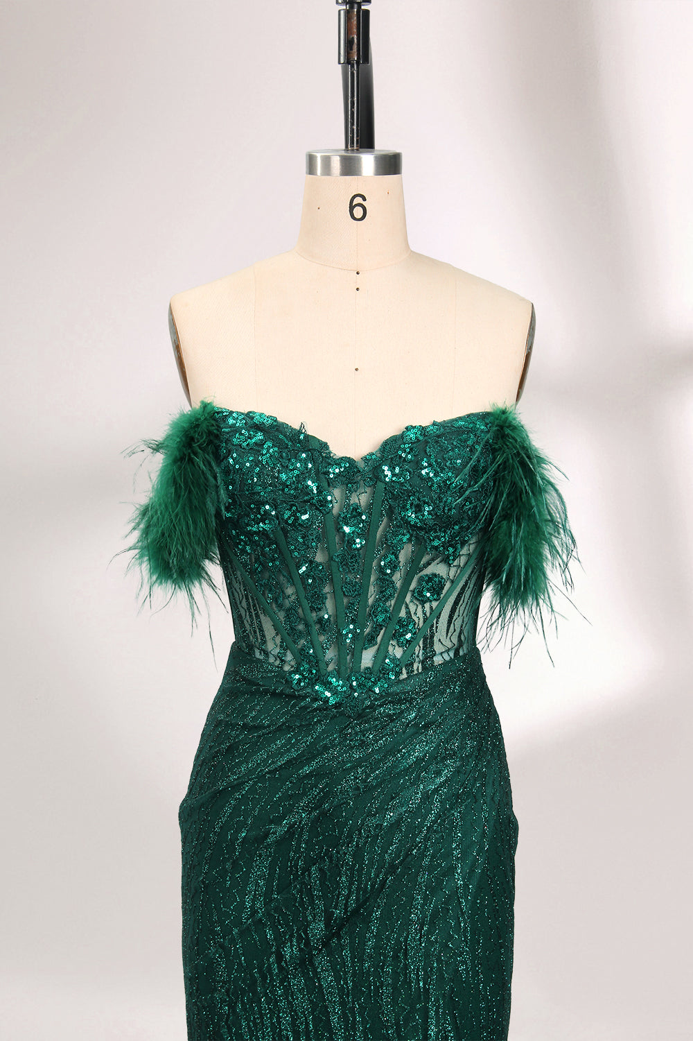 A mannequin displays a dark green strapless evening gown. It has feather - trimmed cups and a sequined, form - fitting skirt that reaches the floor, with a side slit. The intricate design and shimmering texture make it elegant for formal events.03