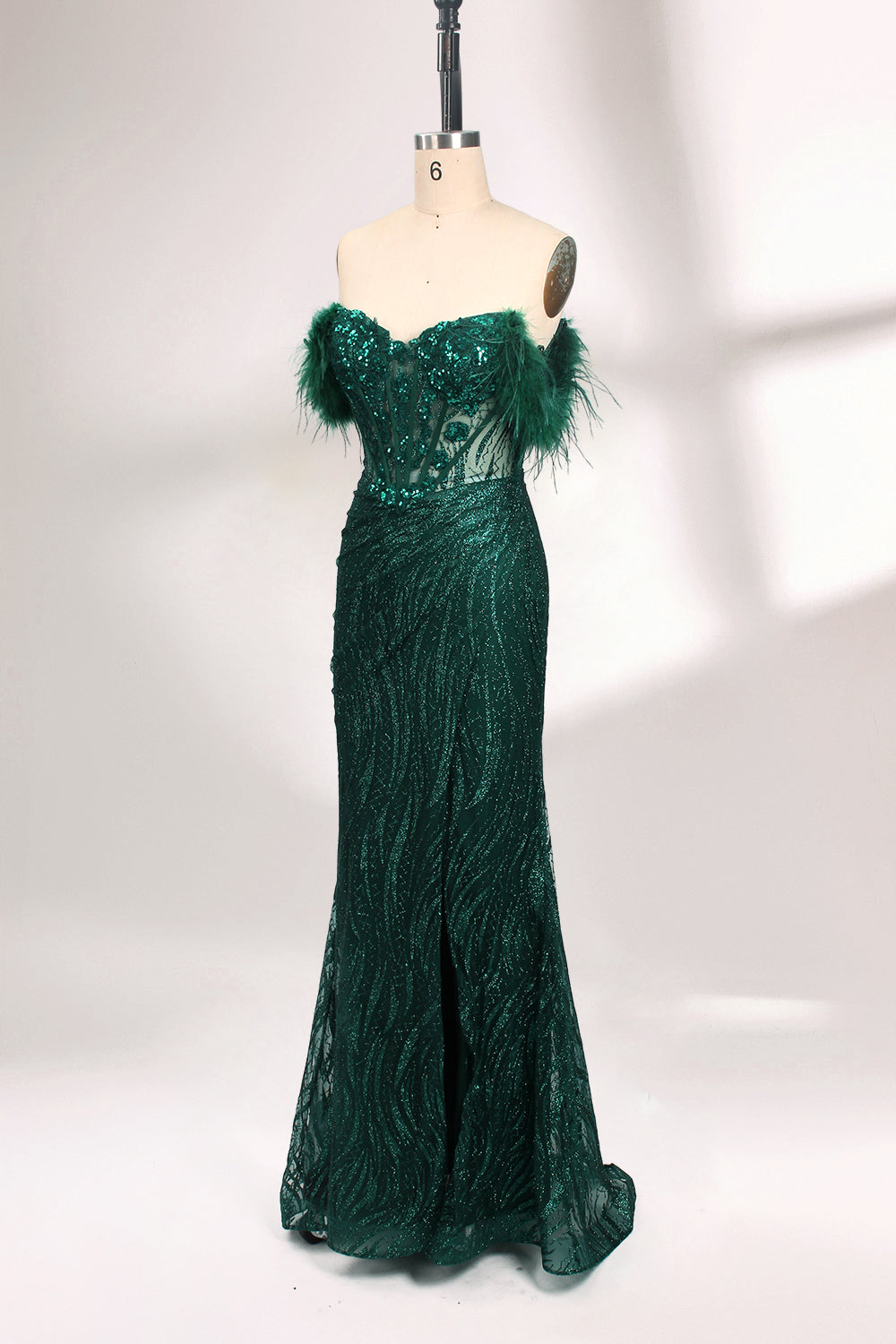 A mannequin displays a dark green strapless evening gown. It has feather - trimmed cups and a sequined, form - fitting skirt that reaches the floor, with a side slit. The intricate design and shimmering texture make it elegant for formal events.01