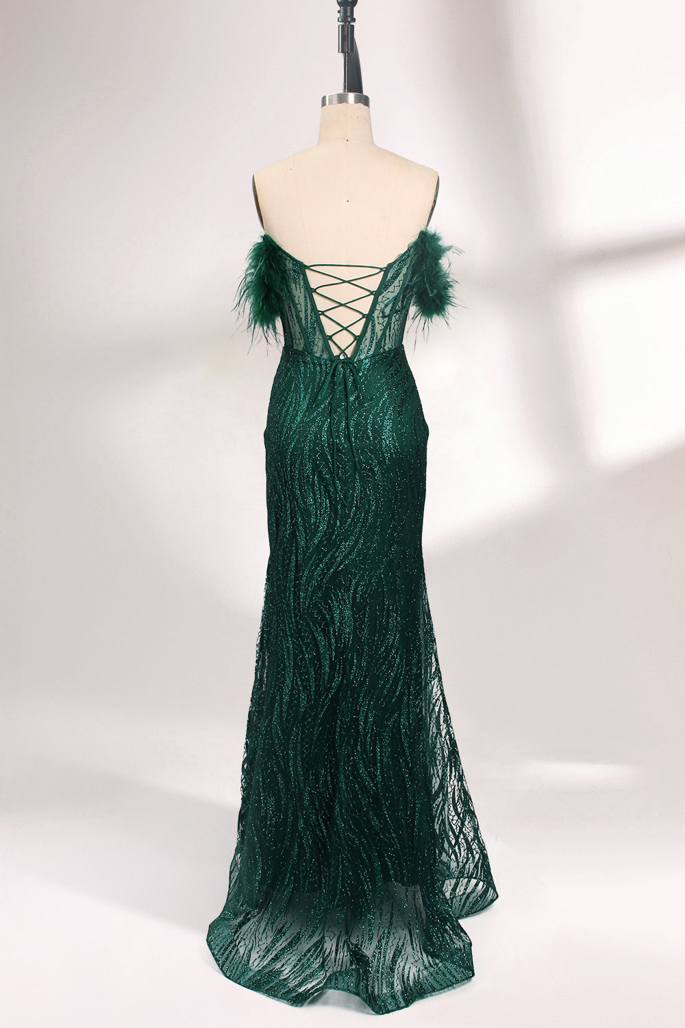 A mannequin displays a dark green strapless evening gown. It has feather - trimmed cups and a sequined, form - fitting skirt that reaches the floor, with a side slit. The intricate design and shimmering texture make it elegant for formal events.02