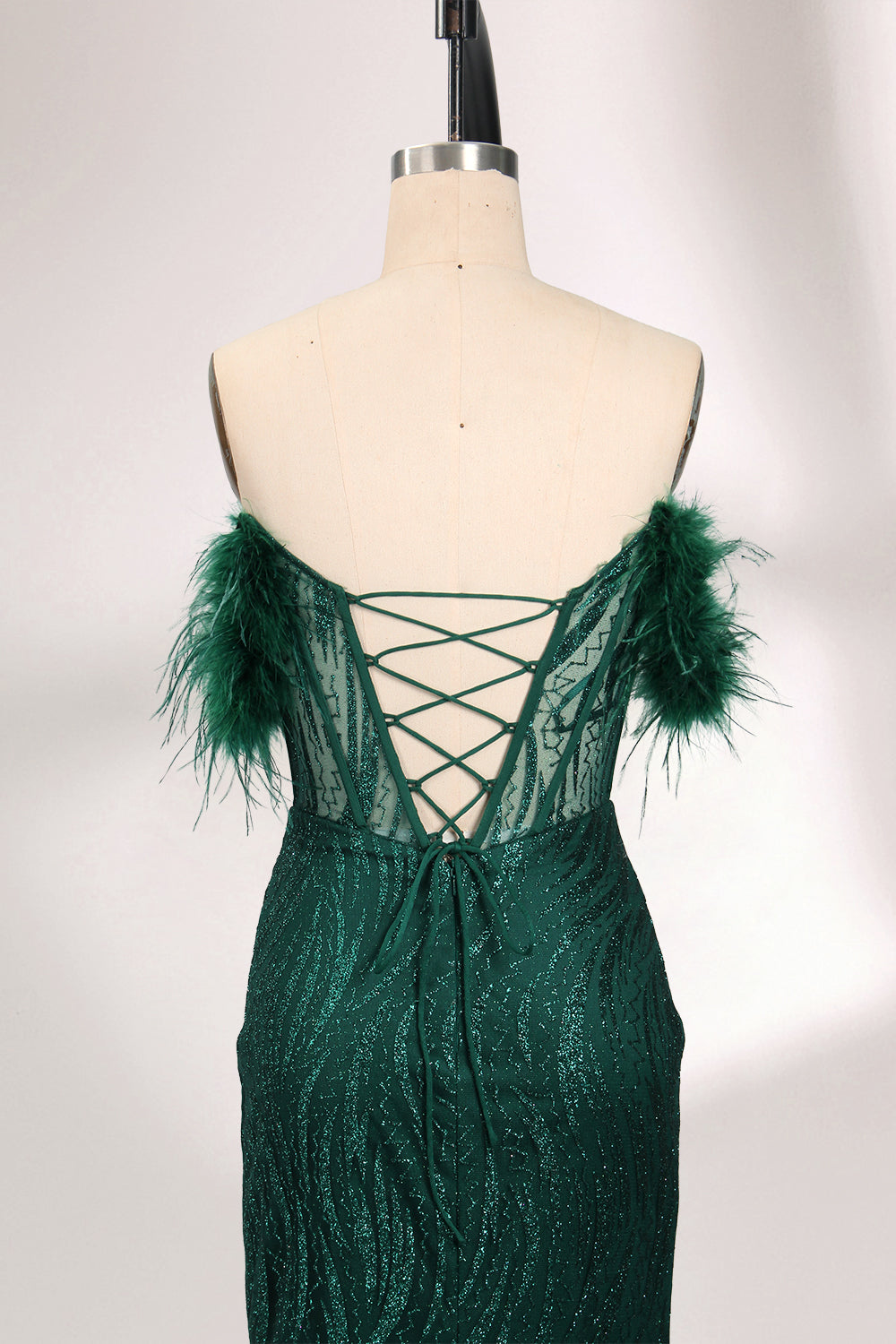 A mannequin displays a dark green strapless evening gown. It has feather - trimmed cups and a sequined, form - fitting skirt that reaches the floor, with a side slit. The intricate design and shimmering texture make it elegant for formal events.05