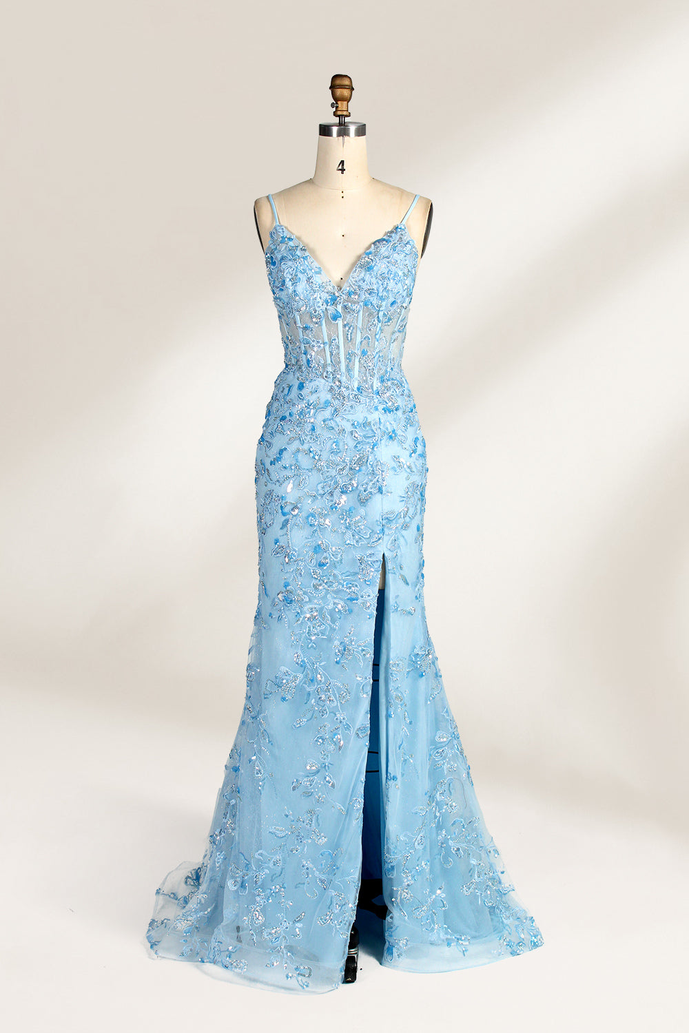 A mannequin showcases a light - blue tulle gown. It has thin straps, a V - neck, floral embroidery, and a high side slit. The intricate design, with sheer bodice details, suits formal events like galas or proms, radiating elegance and charm.1