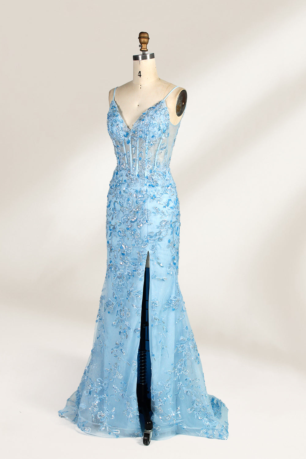 A mannequin showcases a light - blue tulle gown. It has thin straps, a V - neck, floral embroidery, and a high side slit. The intricate design, with sheer bodice details, suits formal events like galas or proms, radiating elegance and charm.4