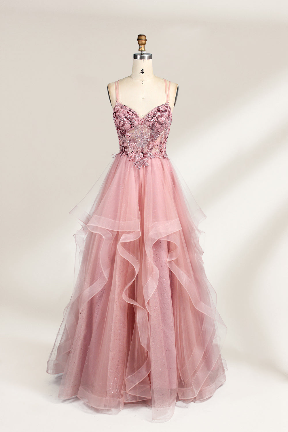 A mannequin displays a pink tulle gown. It features thin straps, a sweetheart neckline, intricate floral appliqués with sequins on the bodice, and a multi - layered, ruffled tulle skirt. The elegant design creates a romantic and glamorous look, perfect for formal events like proms or weddings.1