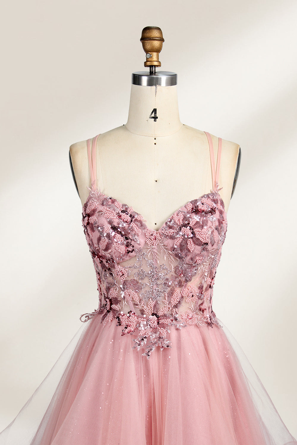 A mannequin displays a pink tulle gown. It features thin straps, a sweetheart neckline, intricate floral appliqués with sequins on the bodice, and a multi - layered, ruffled tulle skirt. The elegant design creates a romantic and glamorous look, perfect for formal events like proms or weddings.4