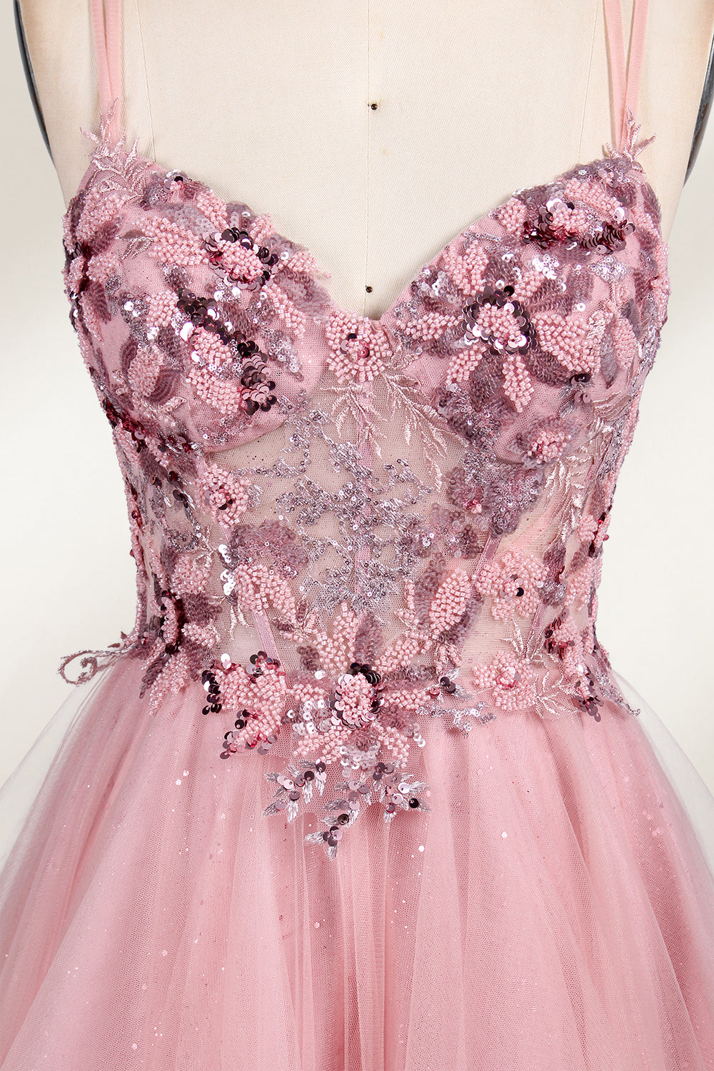 A mannequin displays a pink tulle gown. It features thin straps, a sweetheart neckline, intricate floral appliqués with sequins on the bodice, and a multi - layered, ruffled tulle skirt. The elegant design creates a romantic and glamorous look, perfect for formal events like proms or weddings.6