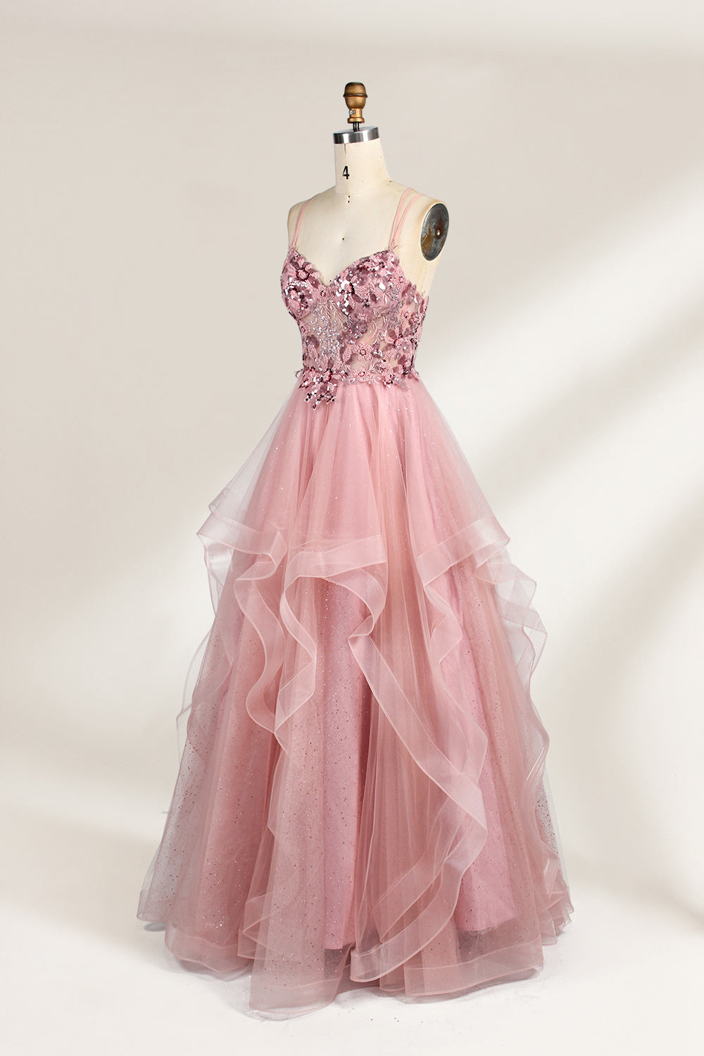 A mannequin displays a pink tulle gown. It features thin straps, a sweetheart neckline, intricate floral appliqués with sequins on the bodice, and a multi - layered, ruffled tulle skirt. The elegant design creates a romantic and glamorous look, perfect for formal events like proms or weddings.3