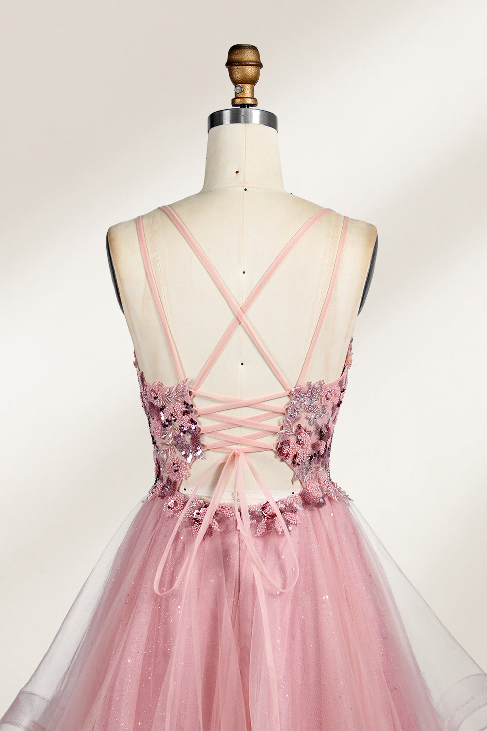A mannequin displays a pink tulle gown. It features thin straps, a sweetheart neckline, intricate floral appliqués with sequins on the bodice, and a multi - layered, ruffled tulle skirt. The elegant design creates a romantic and glamorous look, perfect for formal events like proms or weddings.5