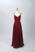 Photograph of a blue, floor-length, sleeveless gown with intricate lace detailing on the bodice and a subtle thigh-high slit, displayed on a mannequin. The gown has a fitted top and a flowing, soft fabric skirt. The background is plain beige.07