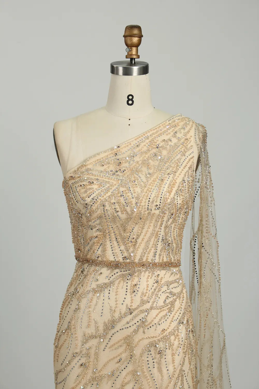 One-shoulder champagne sequin bodice with diagonal drape and sparkling beaded details