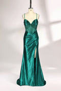 A mannequin displays a green satin gown against a light backdrop. It has thin straps, a sweetheart neckline, and a sheer bodice with beading. The mermaid skirt, featuring a high side slit, combines elegance and allure, perfect for formal galas.1