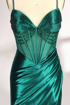A mannequin displays a green satin gown against a light backdrop. It has thin straps, a sweetheart neckline, and a sheer bodice with beading. The mermaid skirt, featuring a high side slit, combines elegance and allure, perfect for formal galas.4