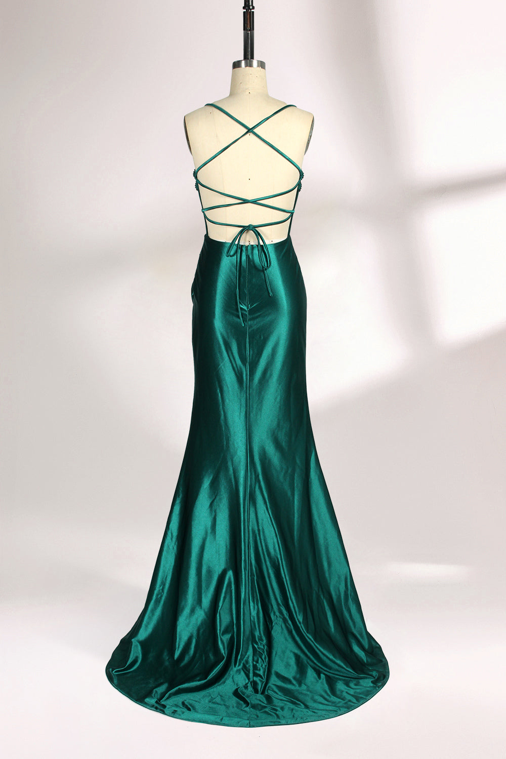 A mannequin displays a green satin gown against a light backdrop. It has thin straps, a sweetheart neckline, and a sheer bodice with beading. The mermaid skirt, featuring a high side slit, combines elegance and allure, perfect for formal galas.2