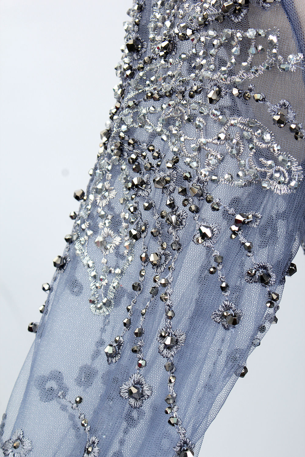 Presented on a mannequin is a blue - toned evening gown. It has a high neckline, long sheer sleeves, and intricate floral embroidery. The elegant design gives off a luxurious and sophisticated vibe, ideal for formal occasions.9