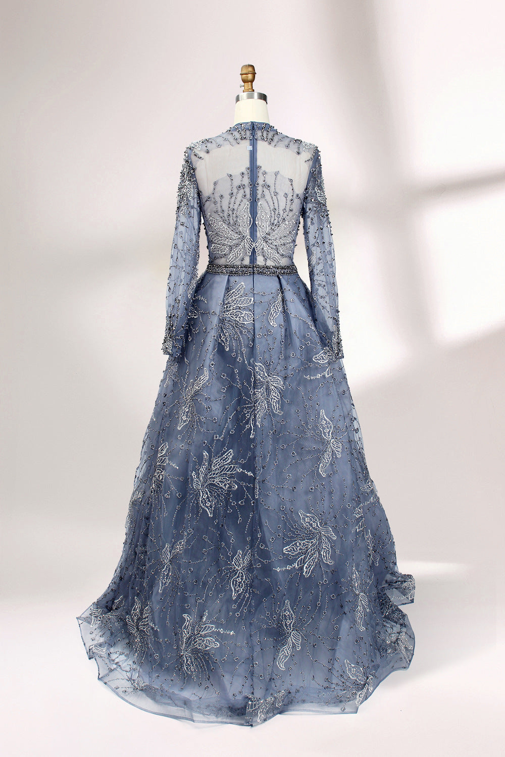 Presented on a mannequin is a blue - toned evening gown. It has a high neckline, long sheer sleeves, and intricate floral embroidery. The elegant design gives off a luxurious and sophisticated vibe, ideal for formal occasions.2