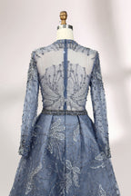 Presented on a mannequin is a blue - toned evening gown. It has a high neckline, long sheer sleeves, and intricate floral embroidery. The elegant design gives off a luxurious and sophisticated vibe, ideal for formal occasions.8