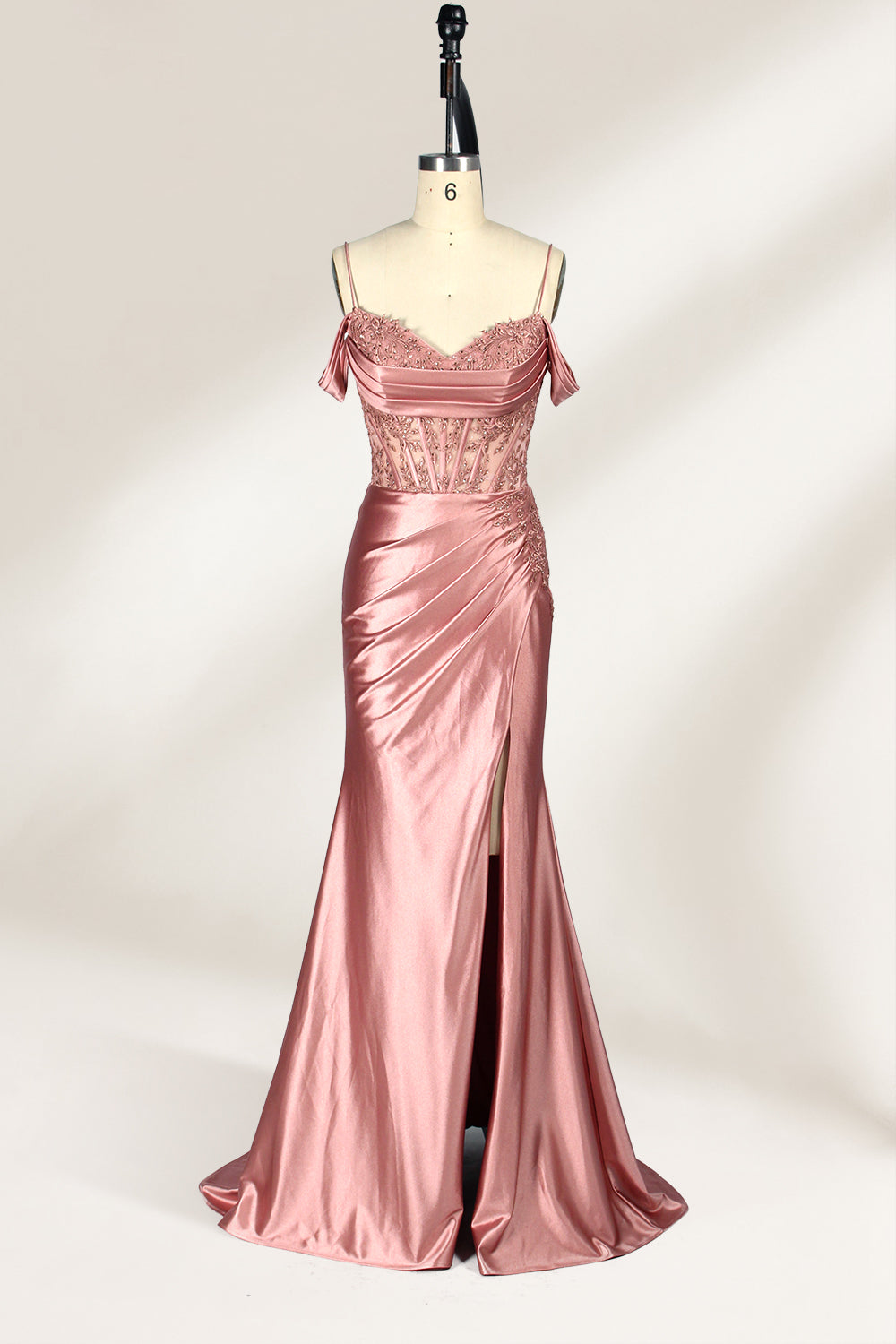 A mannequin displays a rose - gold satin gown. It has thin straps, off - shoulder lace - detailed sleeves, a ruched bodice, and a high side slit. The elegant design, blending satin and lace, suits formal events like galas or weddings.1