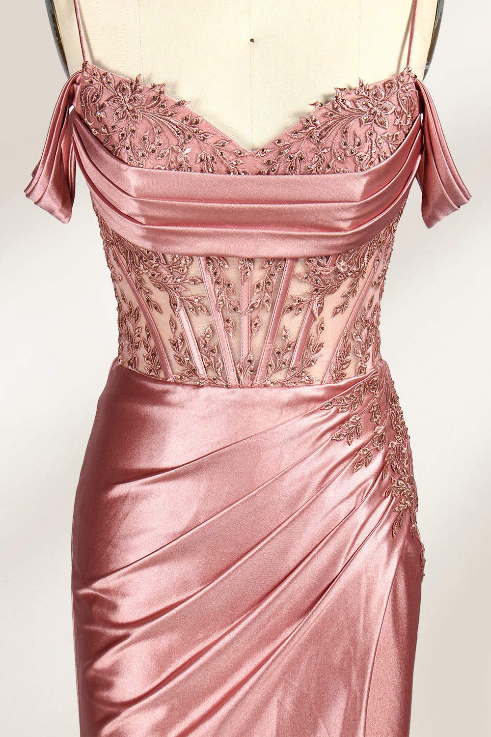 A mannequin displays a rose - gold satin gown. It has thin straps, off - shoulder lace - detailed sleeves, a ruched bodice, and a high side slit. The elegant design, blending satin and lace, suits formal events like galas or weddings.3