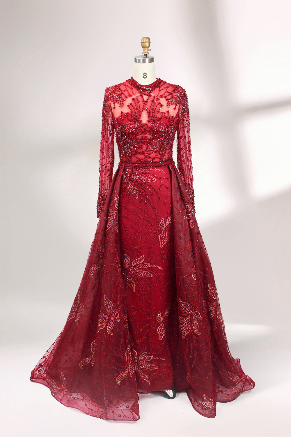 Presented on a mannequin is a blue - toned evening gown. It has a high neckline, long sheer sleeves, and intricate floral embroidery. The elegant design gives off a luxurious and sophisticated vibe, ideal for formal occasions.1