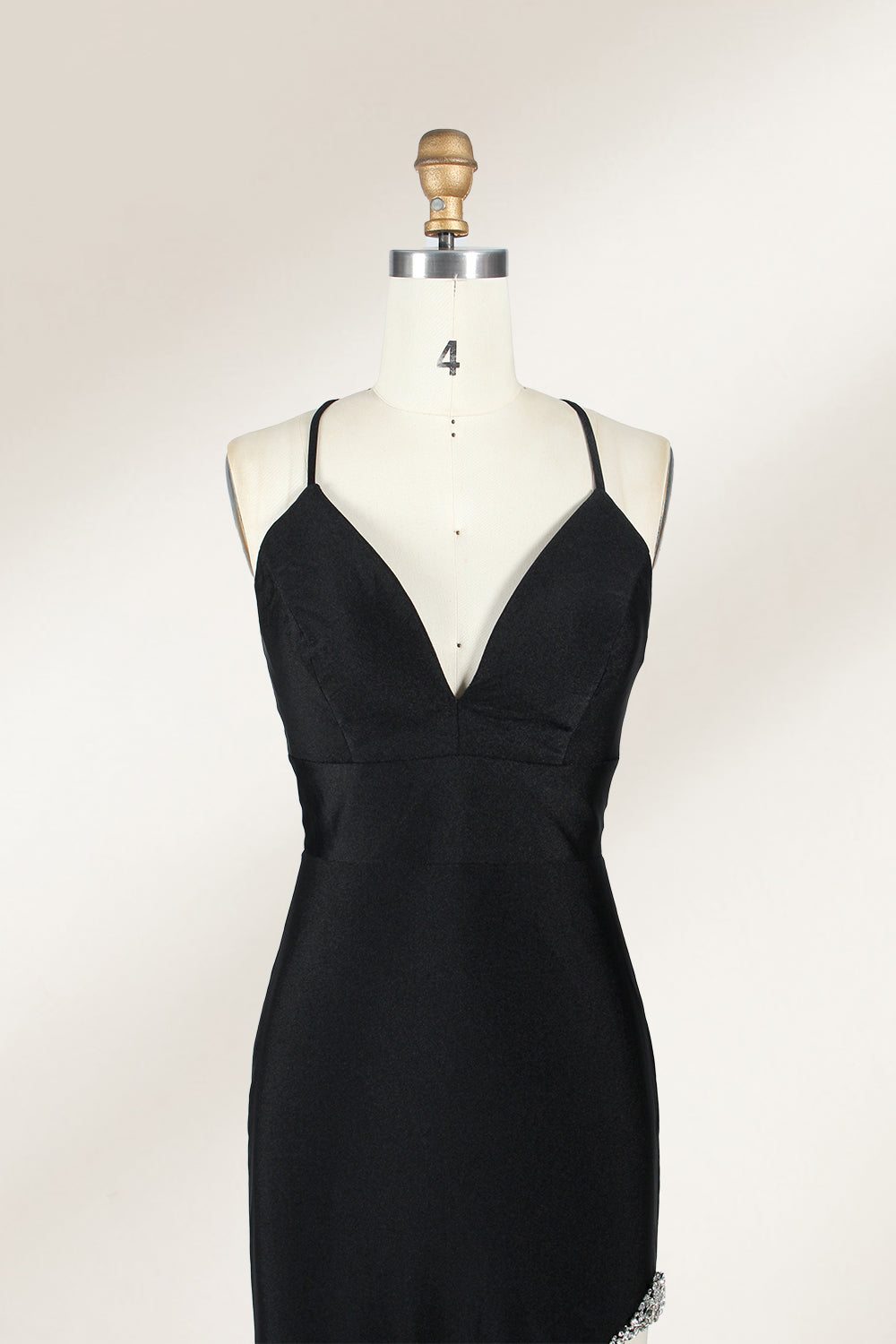 Displayed on a mannequin is a black evening gown. It features spaghetti straps, a deep V - neck, and a high slit with crystal detailing, creating a sleek and glamorous look for formal events.4
