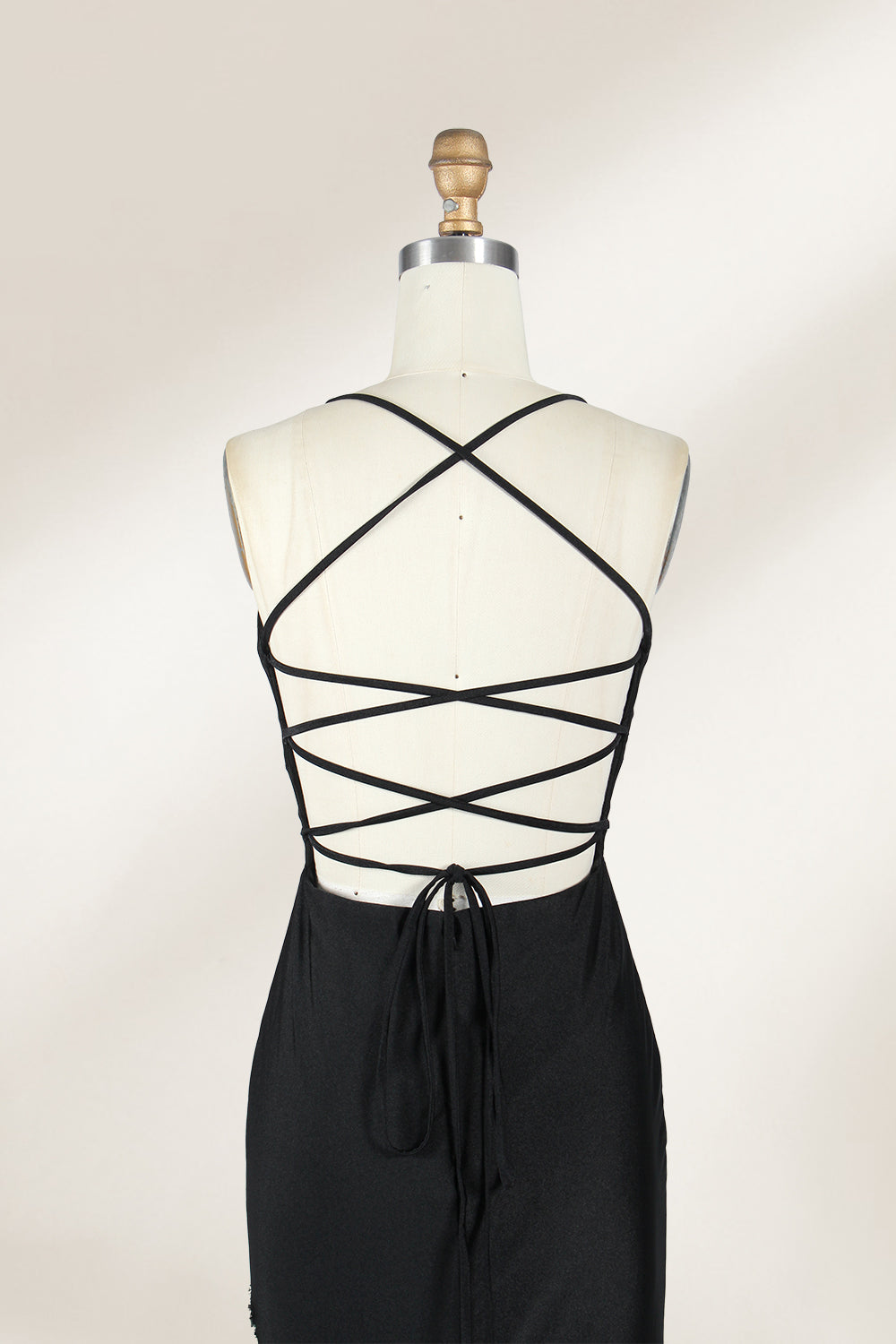 Displayed on a mannequin is a black evening gown. It features spaghetti straps, a deep V - neck, and a high slit with crystal detailing, creating a sleek and glamorous look for formal events.6