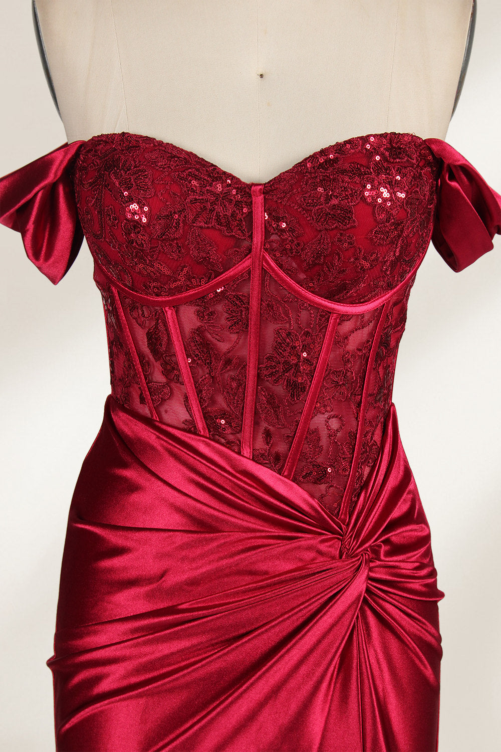 Against a light - hued backdrop, a mannequin displays a strapless red satin gown. It boasts off - shoulder ruffled sleeves, a lace - detailed bodice, and a high side slit. The ruched satin skirt and sequin - adorned top exude charm, suitable for formal dinners or galas.3